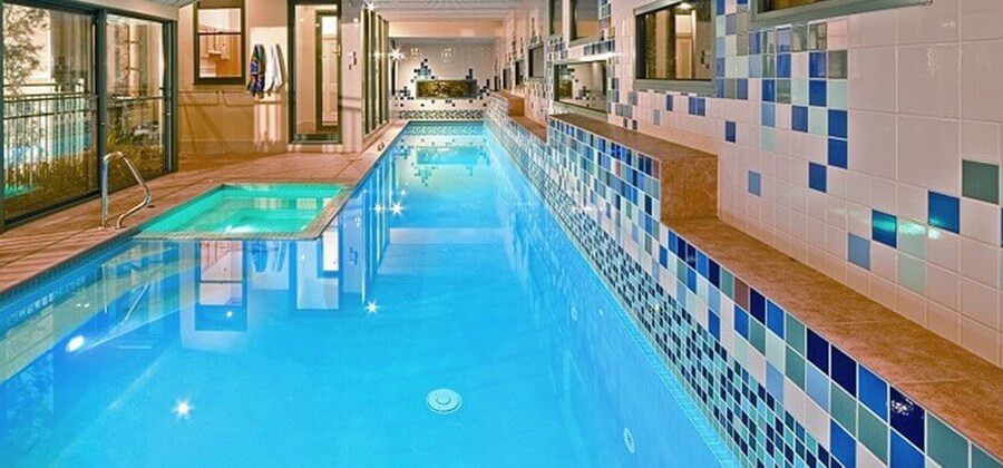Indoor lap pool with a spa by Natural Pools